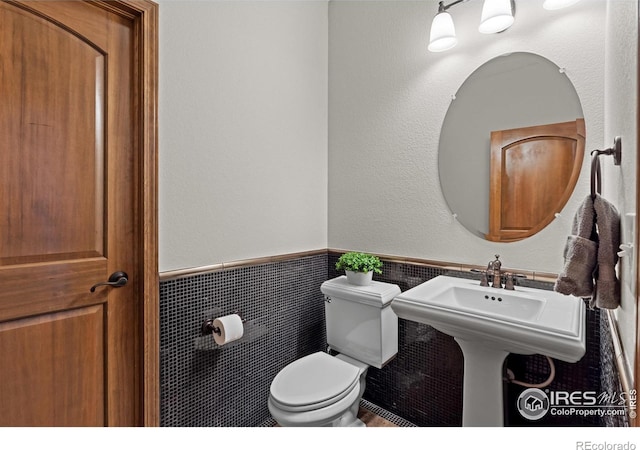 4822 Raven Run, Broomfield, CO 80023 - half bath featuring a wainscoted wall, toilet, and tile walls