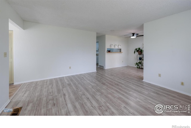 unfurnished living room with visible vents, wood finished floors, baseboards, ceiling fan, and a textured ceiling