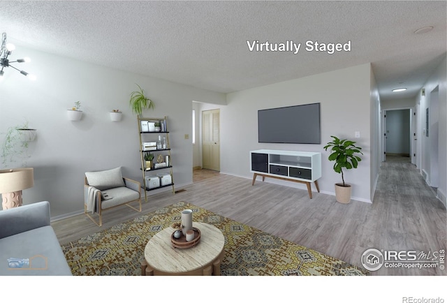living room featuring a textured ceiling, baseboards, and wood finished floors