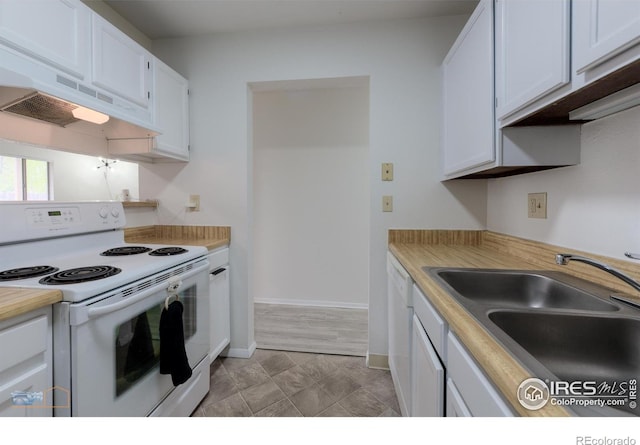 kitchen featuring white appliances, premium range hood, light countertops, white cabinets, and a sink