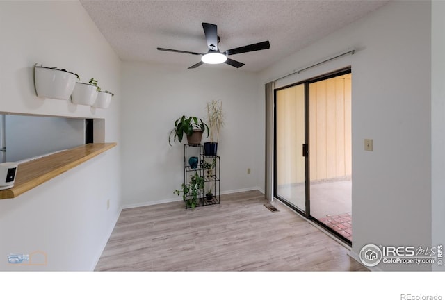 unfurnished room with a textured ceiling, a ceiling fan, baseboards, wood finished floors, and visible vents
