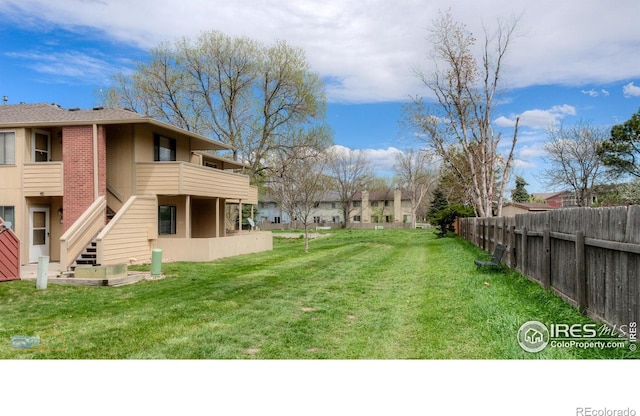 view of yard with fence and a balcony