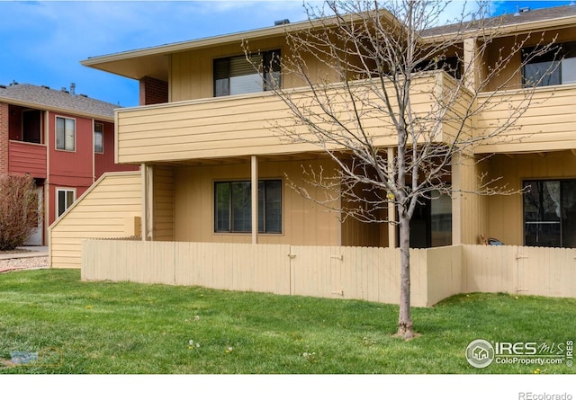 view of property exterior featuring a yard, fence, and a balcony