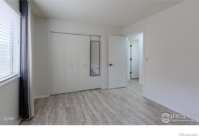 unfurnished bedroom with baseboards, wood finished floors, and a closet