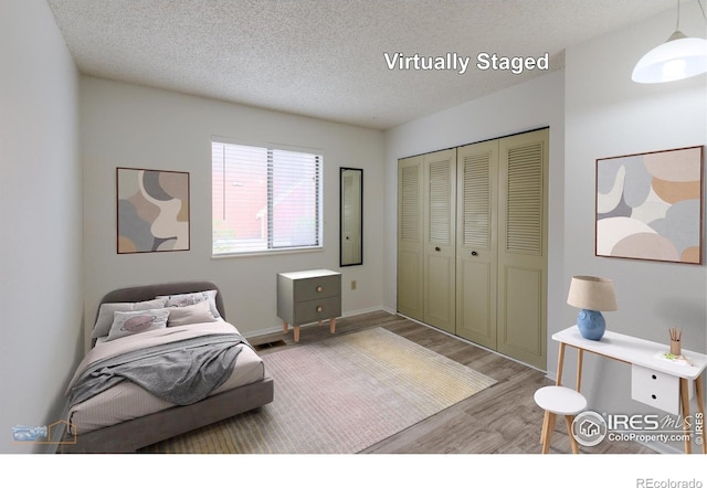 bedroom with a textured ceiling, baseboards, a closet, and wood finished floors