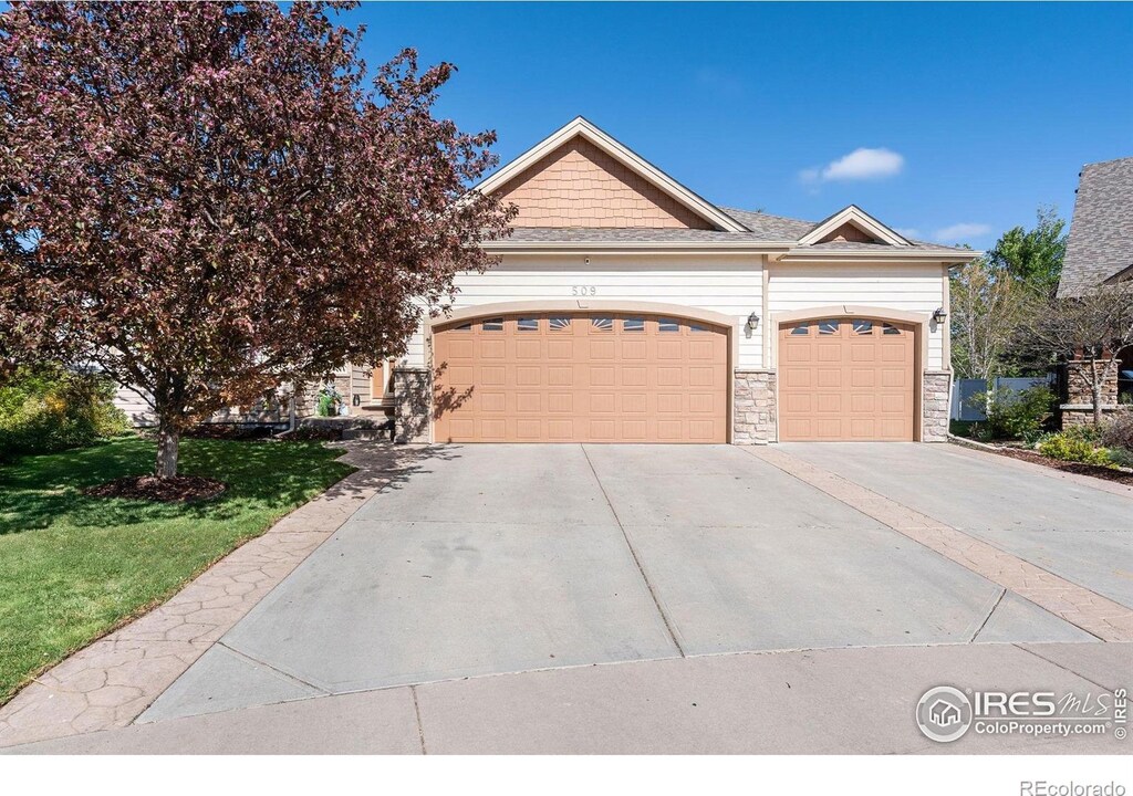 509 Trout Creek Ct, Windsor, CO 80550 - view of front of home featuring a front yard, an attached garage, driveway, and stone siding