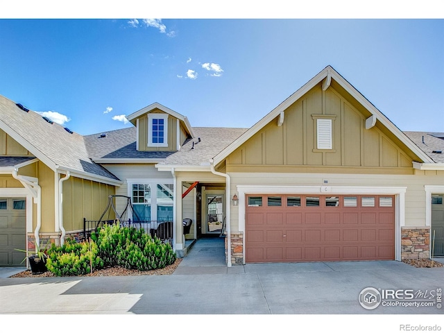 14394 W 88th Dr Unit C, Arvada, CO 80005 - craftsman-style house featuring board and batten siding, roof with shingles, a garage, concrete driveway, and stone siding