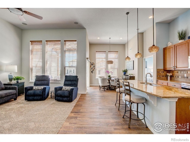14394 W 88th Dr Unit C, Arvada, CO 80005 - kitchen with wood finished floors, open floor plan, a breakfast bar area, light stone counters, and a sink