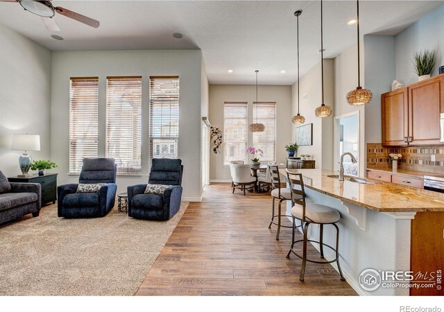14394 W 88th Dr Unit C, Arvada, CO 80005 - kitchen with a breakfast bar, light wood-style flooring, open floor plan, light stone counters, and a ceiling fan