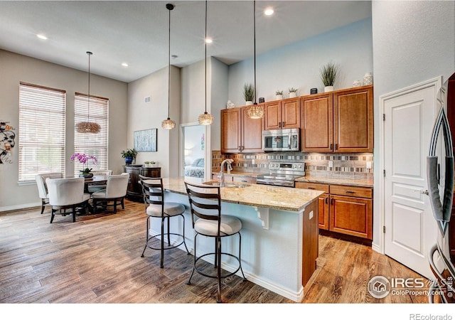 14394 W 88th Dr Unit C, Arvada, CO 80005 - kitchen featuring backsplash, appliances with stainless steel finishes, brown cabinets, a sink, and light stone counters