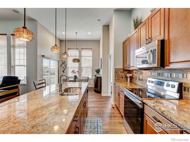 14394 W 88th Dr Unit C, Arvada, CO 80005 - kitchen featuring decorative backsplash, light wood-type flooring, a sink, light stone counters, and stainless steel appliances