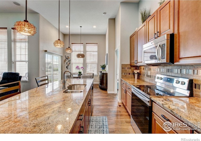 14394 W 88th Dr Unit C, Arvada, CO 80005 - kitchen with stainless steel appliances, light wood finished floors, decorative backsplash, light stone counters, and recessed lighting