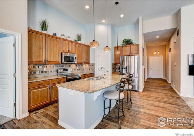14394 W 88th Dr Unit C, Arvada, CO 80005 - kitchen featuring appliances with stainless steel finishes, brown cabinetry, a sink, and light wood-style floors