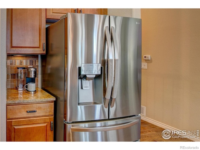 14394 W 88th Dr Unit C, Arvada, CO 80005 - kitchen with brown cabinets, light wood finished floors, stainless steel fridge with ice dispenser, baseboards, and backsplash
