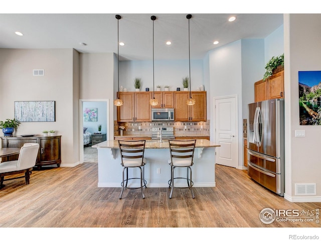 14394 W 88th Dr Unit C, Arvada, CO 80005 - kitchen with brown cabinets, appliances with stainless steel finishes, visible vents, and light wood-type flooring