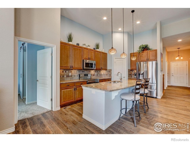 14394 W 88th Dr Unit C, Arvada, CO 80005 - kitchen featuring brown cabinets, a sink, light wood finished floors, a high ceiling, and stainless steel appliances