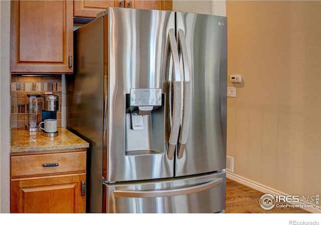 14394 W 88th Dr Unit C, Arvada, CO 80005 - kitchen with stainless steel fridge with ice dispenser, decorative backsplash, wood finished floors, and brown cabinetry