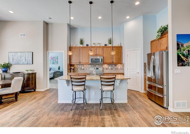 14394 W 88th Dr Unit C, Arvada, CO 80005 - kitchen featuring appliances with stainless steel finishes, light wood finished floors, brown cabinets, light stone countertops, and recessed lighting