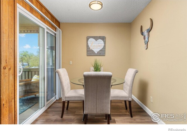 dining area with baseboards, a textured ceiling, and wood finished floors