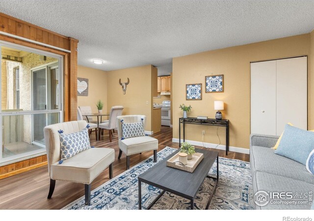 living area with baseboards, a textured ceiling, and wood finished floors