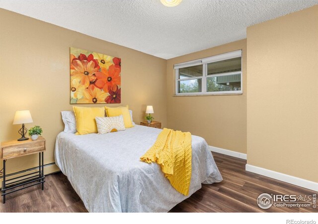 bedroom featuring baseboards, a textured ceiling, wood finished floors, and baseboard heating