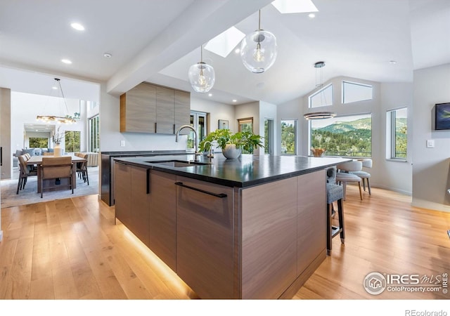 50 Wildwood Ln, Boulder, CO 80304 - kitchen featuring modern cabinets, dark countertops, light wood finished floors, vaulted ceiling, and an island with sink
