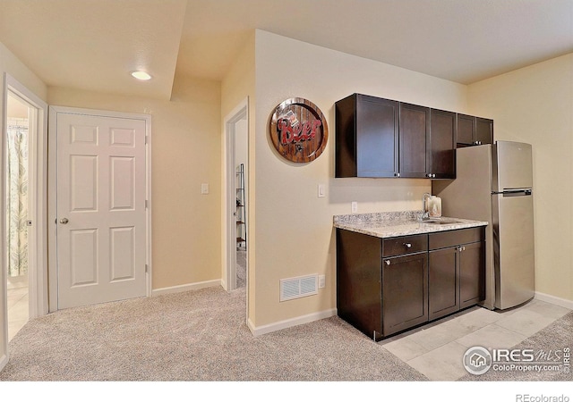 2927 Percheron Dr, Fort Collins, CO 80525 - kitchen with dark brown cabinetry, visible vents, a sink, baseboards, and freestanding refrigerator