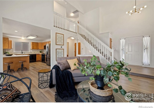1532 Corydalis Ct, Fort Collins, CO 80526 - living room with light wood-style flooring, a towering ceiling, stairway, a chandelier, and arched walkways