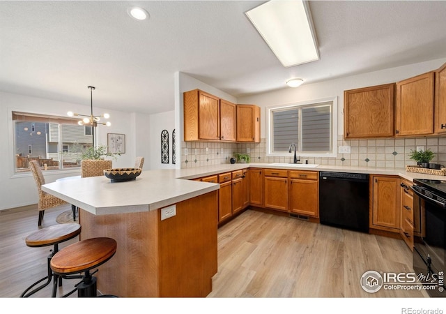 1532 Corydalis Ct, Fort Collins, CO 80526 - kitchen with black appliances, a sink, a breakfast bar, a peninsula, and light wood-style floors
