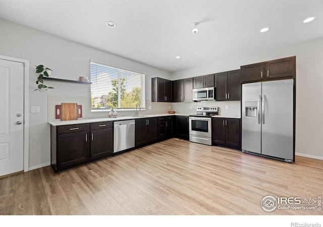 4672 Clear Creek Dr, Longmont, CO 80504 - kitchen with stainless steel appliances, a sink, light wood-style floors, dark brown cabinetry, and light countertops