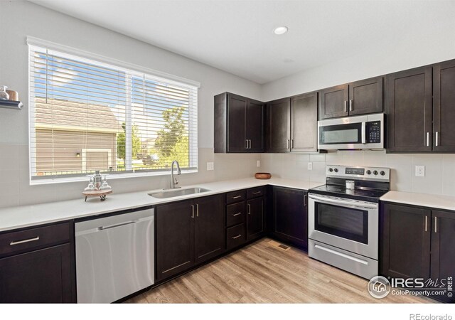 4672 Clear Creek Dr, Longmont, CO 80504 - kitchen with appliances with stainless steel finishes, a sink, light wood finished floors, light countertops, and tasteful backsplash