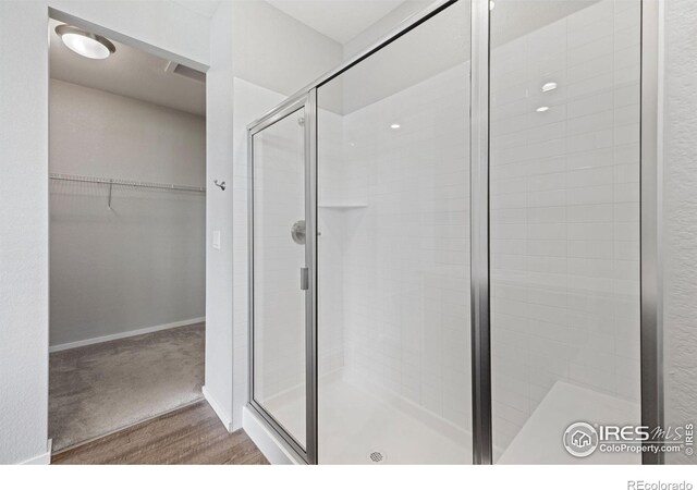 4672 Clear Creek Dr, Longmont, CO 80504 - full bathroom with a stall shower, a walk in closet, wood finished floors, and baseboards