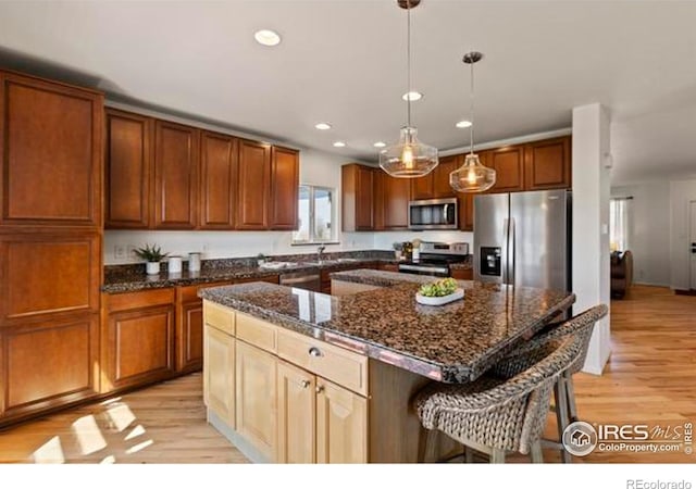 6117 Gold Dust Rd, Timnath, CO 80547 - kitchen with stainless steel appliances, light wood-type flooring, a breakfast bar area, recessed lighting, and a center island