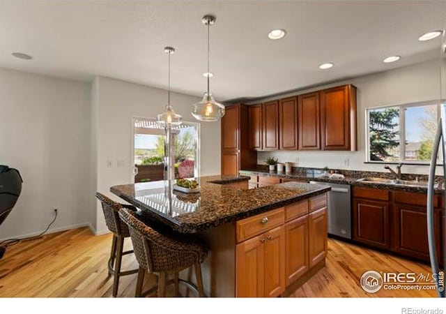 6117 Gold Dust Rd, Timnath, CO 80547 - kitchen featuring stainless steel dishwasher, light wood finished floors, a breakfast bar, recessed lighting, and decorative light fixtures