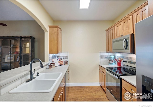 5775 29th St Unit 101, Greeley, CO 80634 - kitchen with appliances with stainless steel finishes, a sink, light wood-style floors, arched walkways, and tasteful backsplash