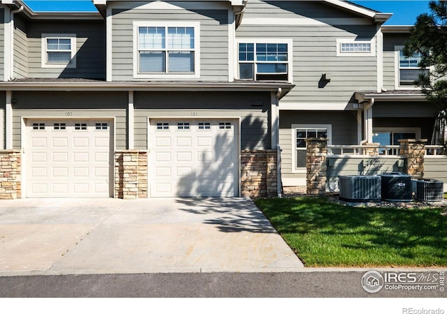 5775 29th St Unit 101, Greeley, CO 80634 - view of front of property with central air condition unit, an attached garage, driveway, and stone siding