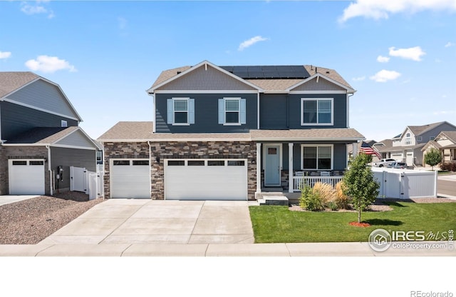 craftsman-style home with fence, a front lawn, a porch, a gate, and solar panels