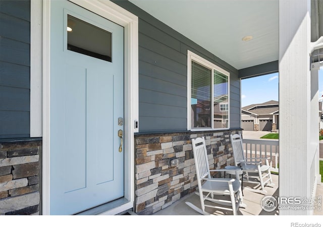 entrance to property with a porch and stone siding