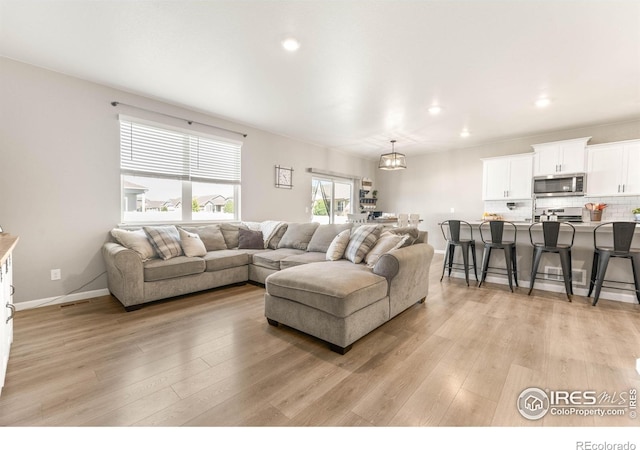 living room featuring light wood-style floors, recessed lighting, and a chandelier