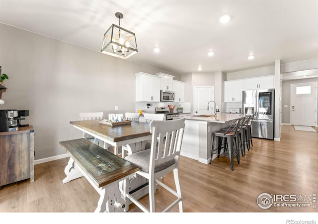 dining area with recessed lighting, baseboards, an inviting chandelier, and light wood-type flooring