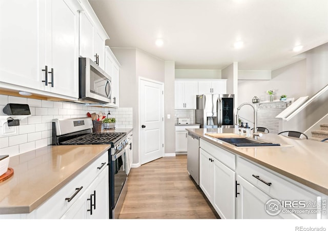 kitchen with white cabinets, appliances with stainless steel finishes, a sink, and tasteful backsplash
