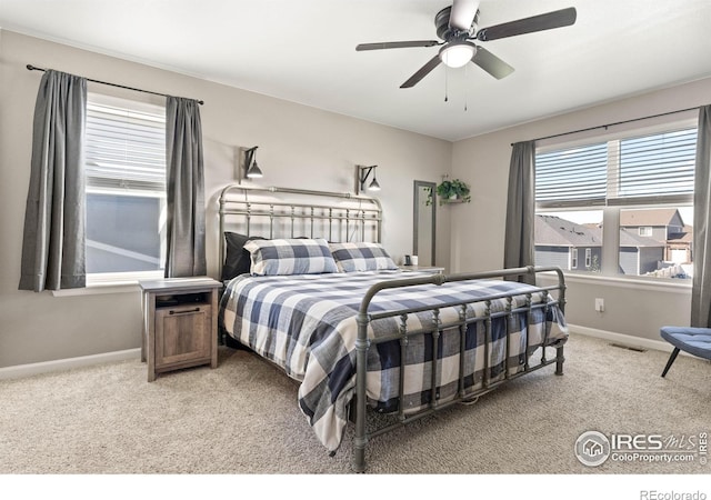 bedroom with baseboards, visible vents, and light carpet
