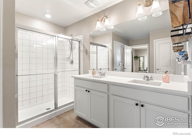 bathroom featuring double vanity, a sink, tile patterned floors, and a shower stall