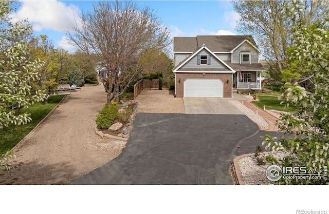view of front facade featuring covered porch, a garage, brick siding, and driveway
