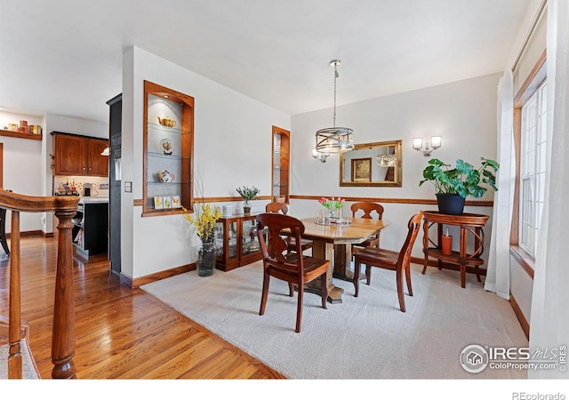 dining room with baseboards, a wealth of natural light, light wood-style flooring, and a chandelier
