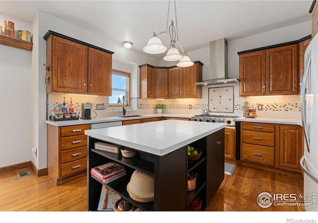 kitchen featuring a sink, wall chimney range hood, wood finished floors, open shelves, and light countertops