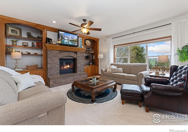 living area with a fireplace, a ceiling fan, and built in shelves