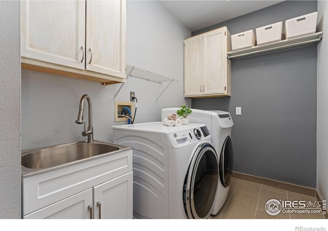 washroom featuring a sink, cabinet space, baseboards, and washer and dryer