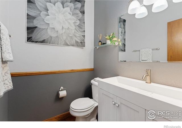 bathroom featuring vanity, toilet, and baseboards