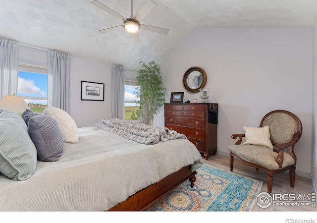 bedroom featuring a ceiling fan, multiple windows, vaulted ceiling, and wood finished floors